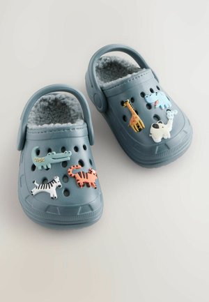 Saboturi albastre din cauciuc cu o căptușeală moale din fleece, decorate cu accesorii în formă de animale, inclusiv o girafă, un câine, un hipopotam, o zebră și un crocodil.