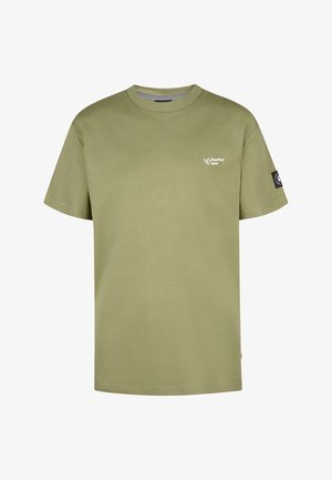 Oliwkowa bawełniana koszulka z krótkim rękawem, z logo na lewej piersi, zestawiona z granatowymi szortami i białymi trampkami z czarnymi akcentami.