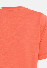 Koral T-shirt lavet af letvægts, tekstureret stof. Har rund halsudskæring og korte ærmer. Synlige syninger langs kanterne.