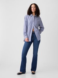 Striped button-up shirt in blue and white, paired with dark blue flared jeans and black flats. The shirt features long sleeves and a relaxed fit.