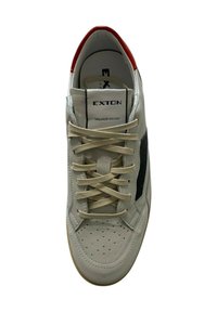 Sneaker in pelle bianca con accenti neri, lacci beige, punta perforata, collare rosso e linguetta con marchio. Suola in gomma per la trazione.