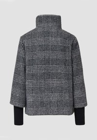 Szary płaszcz w kratę z wysokim kołnierzem, teksturowany materiał i kontrastowe czarne dzianinowe mankiety. Oversize'owy fason z opadającymi ramionami.