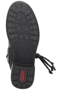 Black rubber shoe sole featuring a textured grip pattern, flat design, and a red logo. Side has a smooth finish with decorative laces.