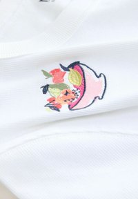 Valge kangas, millel on roosa tikandiga müts, mis hoiab punaste, oranžide, roheliste ja kollaste toonides värvikaid lilli.