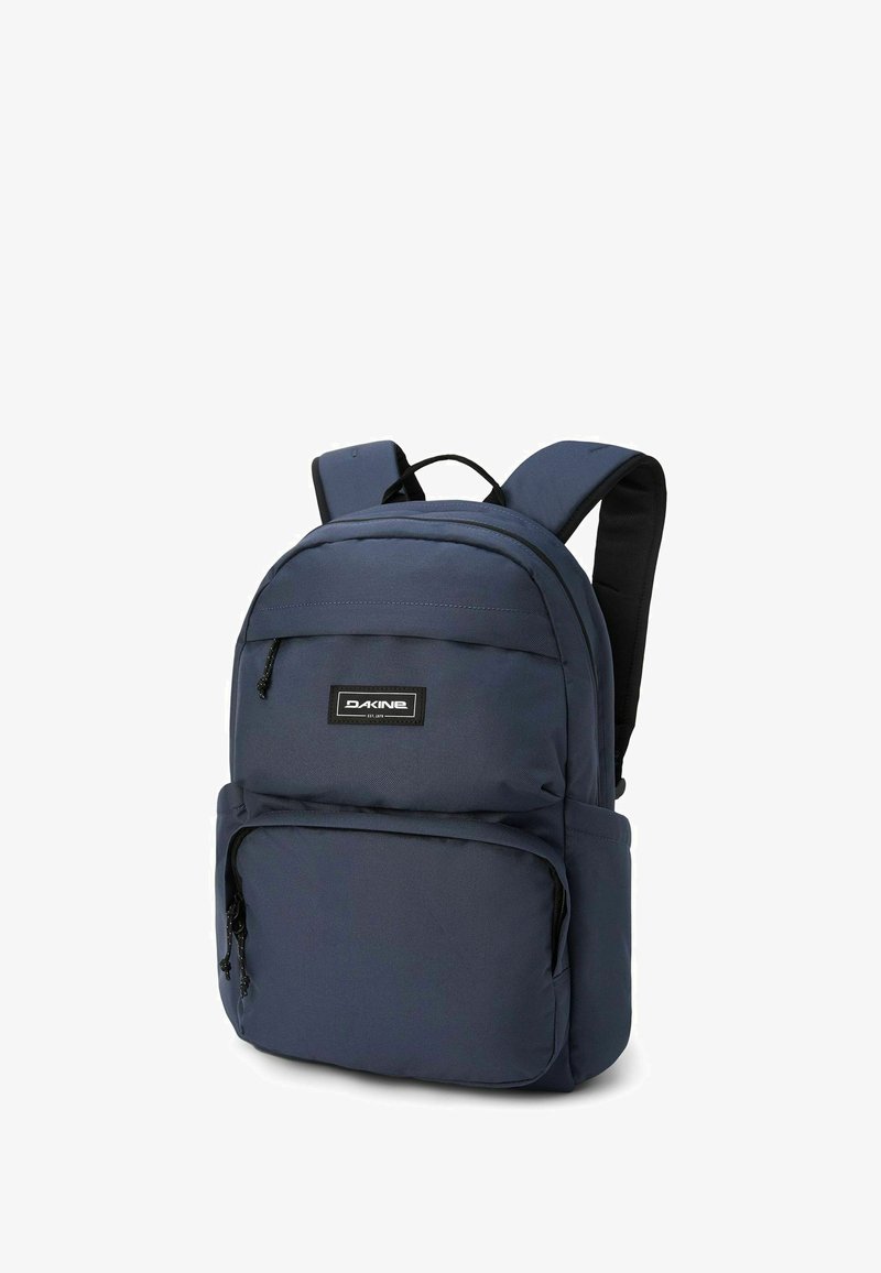 Mochila azul marino con correas de hombro acolchadas dobles, múltiples compartimentos con cremallera y un acabado de tela texturizada. Parche con el logo en la parte delantera.