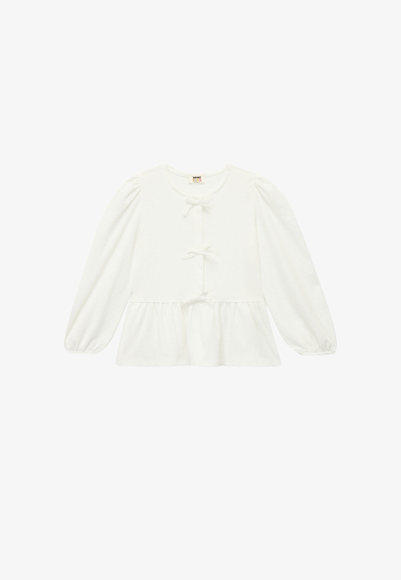 Biała bluzka z długim rękawem, wykonana z teksturowanej tkaniny. Posiada okrągły dekolt, zapięcie na guziki z detalami w postaci kokardek oraz peplum na dole.