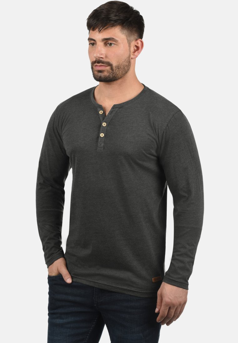 Langärmliges graues Henley-Shirt mit rundem Halsausschnitt und drei Holzknöpfen an der Knopfleiste. Verfügt über einen strukturierten Stoff und ein Logo-Patch.