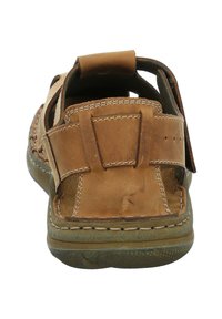 Brown leather sandal with open back, contrasting stitching, and adjustable strap. Textured rubber sole with patterned tread detail.