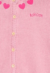 Cardigan rosa lavorato a maglia con applicazioni a forma di cuore sul collo, dotato di chiusura con bottoni e dettagli a costine testurizzati. Logo "BON*ON" ricamato in rosa.