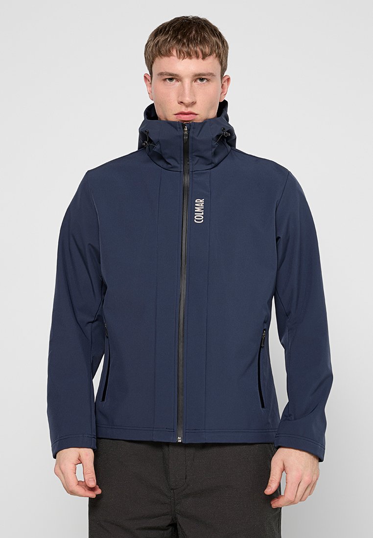 Navyblaue Softshelljacke mit hohem Kragen, durchgehendem Reißverschluss, zwei Seitentaschen und einem Logo auf der oberen linken Seite.