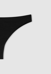 Tanga in cotone nero con una texture liscia e un design minimalista, caratterizzato da un sottile bordo in vita e privo di motivi o decorazioni.