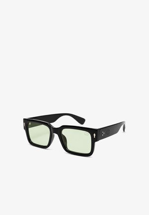 Schwarze rechteckige Sonnenbrille mit dicken Rahmen und hellgrünen getönten Gläsern auf weißem Hintergrund.