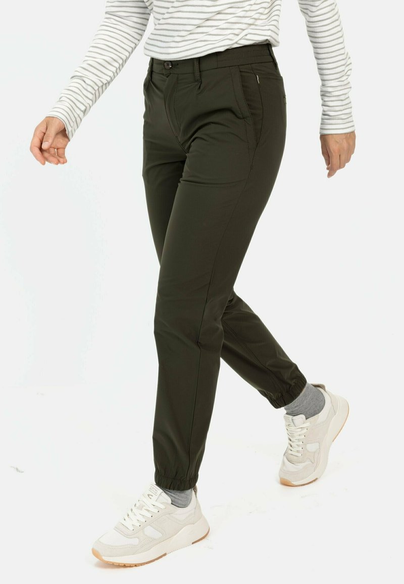 Dunkelgrüne Jogginghosen mit elastischen Bündchen, seitlichen Taschen und einer Reißverschlusstasche; gefertigt aus einem glatten, dehnbaren Material.