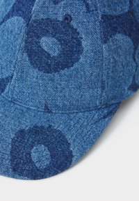 Denim sapka tonal kék körmintával, strukturált árnyékolóval és puha textúrával. A kiemelt varrás és a logó hangsúlyozza a dizájnt.