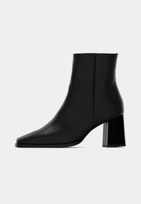 Bottine noire en cuir lisse, dotée d'un bout pointu et d'un talon rectangulaire épais. Design élégant avec une esthétique minimaliste.