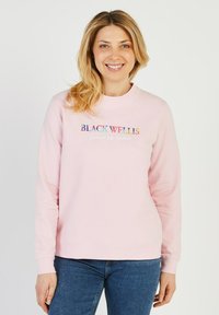Sweatshirt en coton rose à manches longues, col rond, et logo brodé "BLACK WELLS" en texte coloré sur le devant.