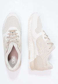 Béžové sportovní boty s vrchní částí z prodyšné síťoviny a syntetického materiálu, texturemi na panelech a tečkovanou bílou střední a podešvou. Šněrovací design a polstrovaný límec.