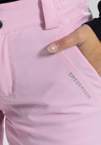 Rosa tights med en slät textur, med en sidficka och en broderad "SWEDEMOUNT"-etikett nära midjan.