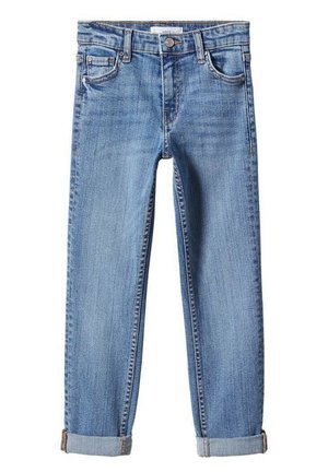 Bambino che indossa una camicia bianca con bottoni sopra una T-shirt bianca, jeans blu rimboccati e scarpe da ginnastica bianche e verdi, in piedi su sfondo bianco.