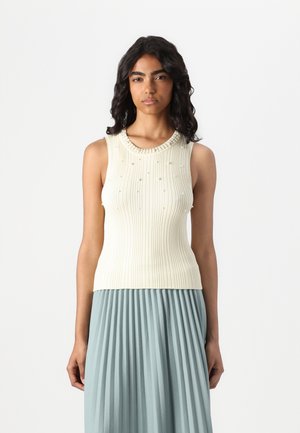Top sin mangas de punto acanalado en tono crema con un escote redondeado texturizado, adornado con pequeñas cuentas decorativas. Combinado con una falda plisada de color azul claro.