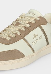 Baskets Replay beiges et marron avec lacets à motifs, détails en daim et logo sur le côté et la languette, présentées sur fond uni.