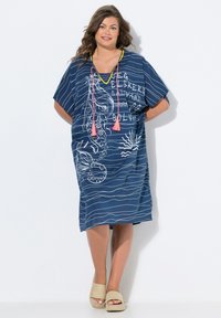 Kaftan rayé bleu et blanc avec une coupe ample, doté d'un col en V, de motifs océaniques blancs et d'accents en franges roses au niveau du col.
