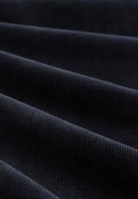 Donkerblauwe corduroy stof met een geribbelde textuur, die zachte, verticale lijnen toont en een gladde afwerking heeft over zijn golvende oppervlak.