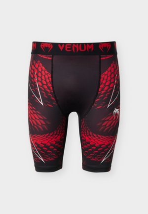 Mustad ja punased kompressioonipüksid, millel on madalate soomuste muster, valged küünisejäljed ja punane "VENUM" logo mustal vööl.