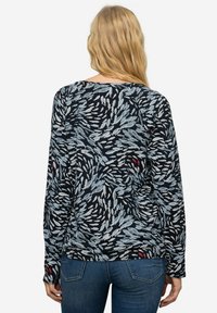 Langsleeve top met een zwarte achtergrond en een draaiend bladerenpatroon in tinten blauw en wit, met kleine rode accenten. Zachte stof.