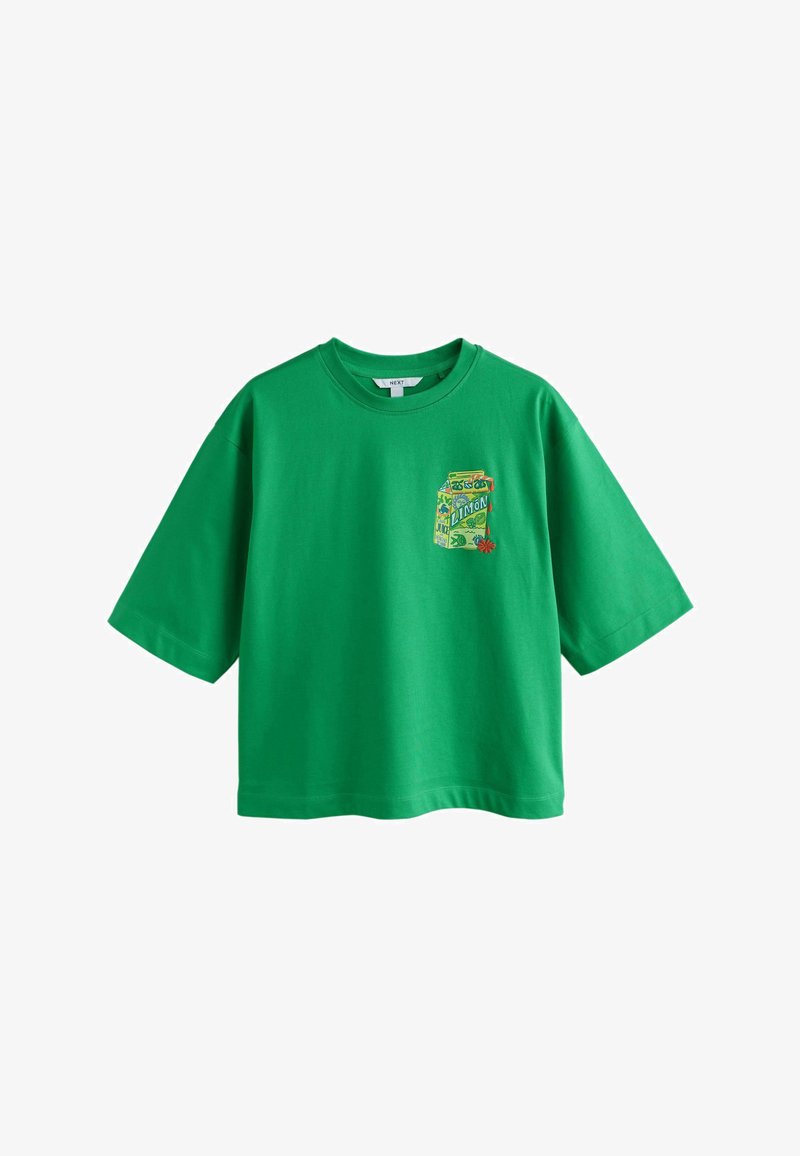 T-shirt vert à manches courtes avec un graphisme coloré d'une brique de jus de citron sur la poitrine gauche, présentant des détails floraux et fruités.