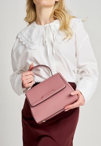 Borsa a mano in pelle rosa chiaro con forma strutturata, manico superiore e finiture nere. Presenta una superficie testurizzata e una chiusura con pattina frontale.