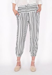 Pantaloni a righe bianche e nere con cintura regolabile, caratterizzati da una vestibilità ampia, polsini elasticizzati e tasche laterali. Dettagli con motivo testurizzato.