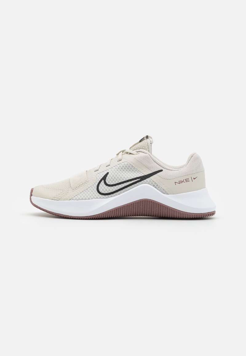 Nike træningssko i beige mesh med sort swoosh, hvid mellemsål og rødbrun tekstureret ydersål. Har snøredesign og polstret krave.