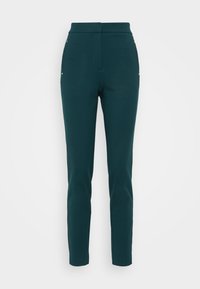Tyrkysové nohavice na mieru s vysokým pásom, slim fit a dekoratívnymi zlatými prvkami po stranách. Hladký materiál bez viditeľných zapínaní.