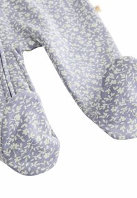 Combinaison légère violette avec un motif floral blanc. Matière en coton doux, manches longues, design avec pieds et détails froncés aux épaules.