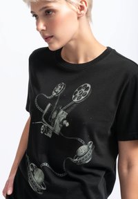 Zwart katoenen T-shirt met een graphic van een filmprojector en planeten met filmspoelen in een gedempte grijs kleur. Ronde halslijn, relaxed fit.