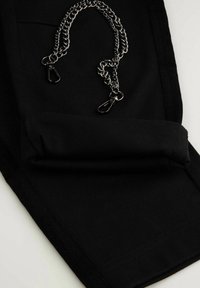 Czarne spodnie z tkaniny z podwiniętym mankietem i metalicznym łańcuszkiem z dwoma klipsami na wierzchu. Gładka faktura z prostym, nowoczesnym krojem.