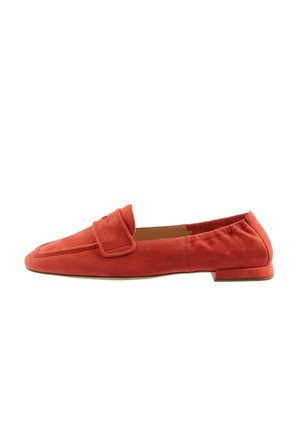 Red suede loafers with a flat heel, featuring a decorative strap across the upper and a smooth, minimalist design.