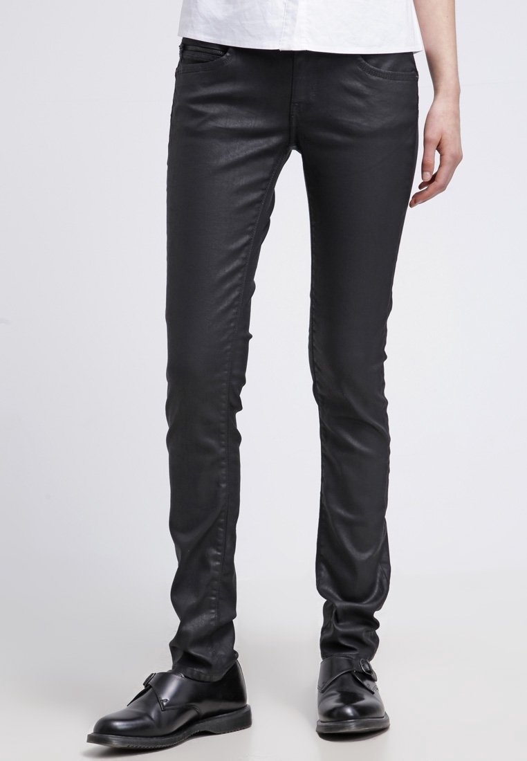 Svarta smala jeans i slätt, glänsande material med framfickor och slim fit, kombinerat med svarta läderskor.