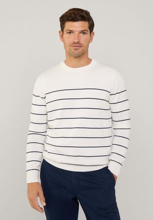 Suéter blanco con rayas horizontales en azul marino, escote redondo y mangas largas. Combinado con pantalones en azul marino, que tienen una textura suave.
