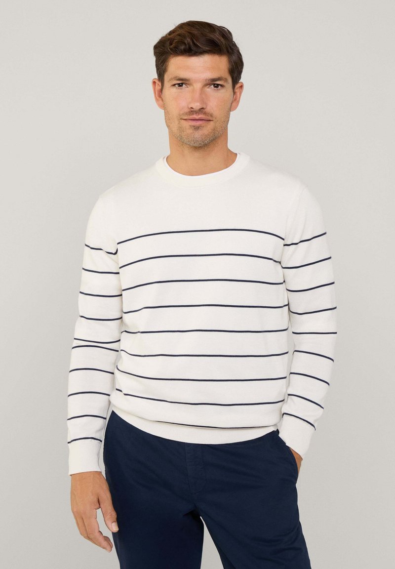 Suéter blanco con rayas horizontales en azul marino, escote redondo y mangas largas. Combinado con pantalones en azul marino, que tienen una textura suave.