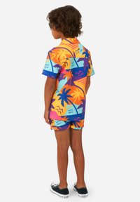 Kleurenset met korte mouwen en shorts met een tropische print van palmbomen, golven en geometrische vormen in oranje, blauw en paars.