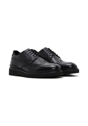 Zapatos de cuero negro con detalles de brogue, que presentan una textura suave, puntera redonda y una suela de goma negra resistente para mayor agarre.
