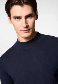 Granatowy, dzianinowy sweter o dopasowanym kroju i wysokim dekolcie, charakteryzujący się gładką teksturą oraz prostymi, czystymi liniami.