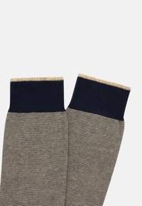 Randiga strumpor med marinblå muddar och en ljus beige kropp med fina horisontella ränder. Mjuk textur, med en vävd finish.