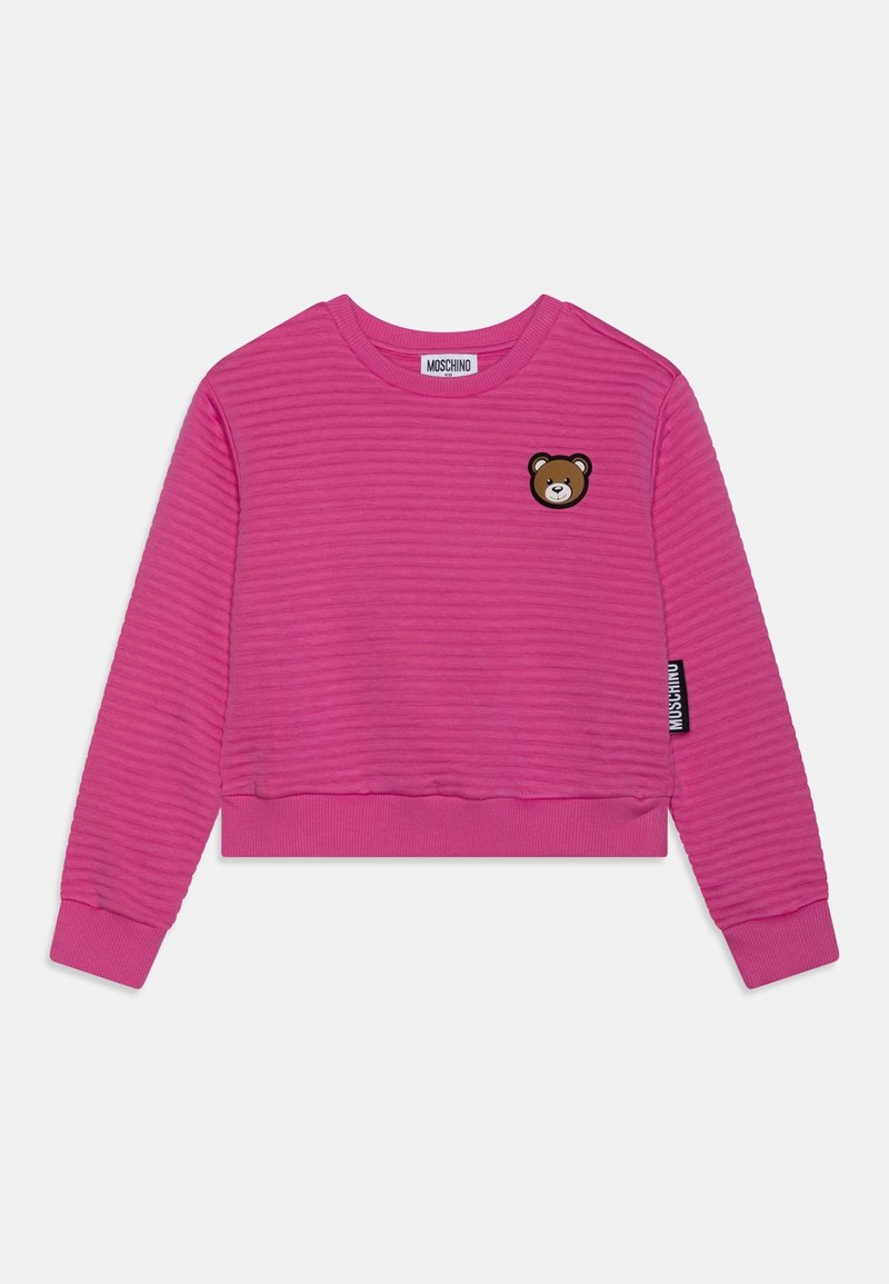 Sweat-shirt à manches longues côtelé rose vif avec un petit patch ours brun sur la poitrine et une étiquette logo Moschino sur le côté.