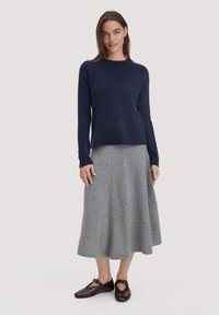 Marineblauer Pullover mit Rundhalsausschnitt, grauer ausgestellter Rock und braune Ballerinas mit Riemen-Details; glatte Textur und schlichte Silhouette.