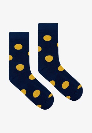 Granatowe skarpetki z żółtymi kropkami, wykonane z miękkiego materiału, z prążkowanym ściągaczem, zaprojektowane dla komfortu i odpowiedniego dopasowania.