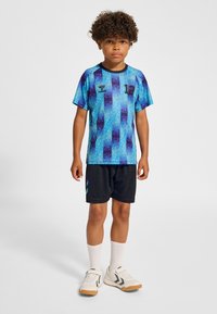 Blå och lila gradientmönstrad sporttröja med svarta shorts. Tröjan har korta ärmar och siffran "12" på framsidan.