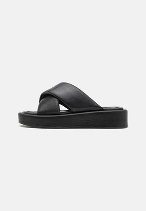 Sorte skinn slide sandaler med kryssremdesign, flat plattformsåle og glatt overflate. Minimalistisk og monokromatisk estetikk.